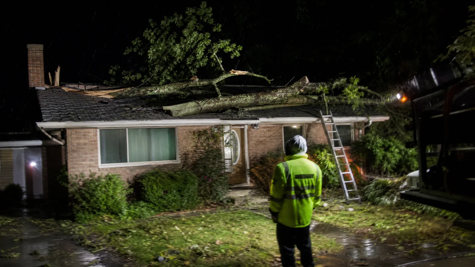 Night storm damage tree removal with a limb across a roof in Grand Rapids MI